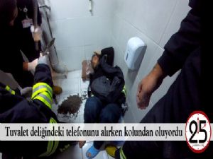 Tuvalet deliğindeki telefonunu alırken kolundan oluyordu