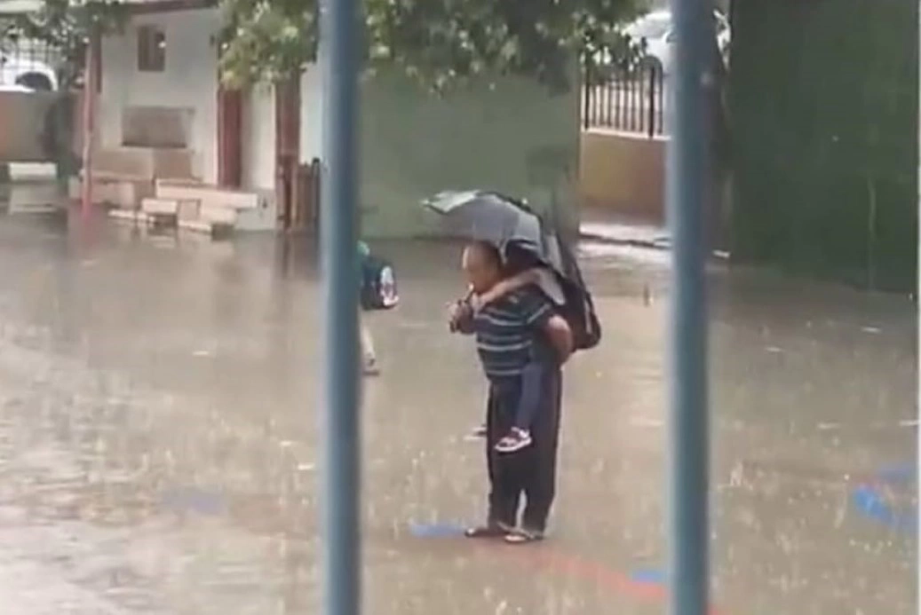 Dede torununu sırtına alarak yağmur altında İstiklal Marşı okudu
